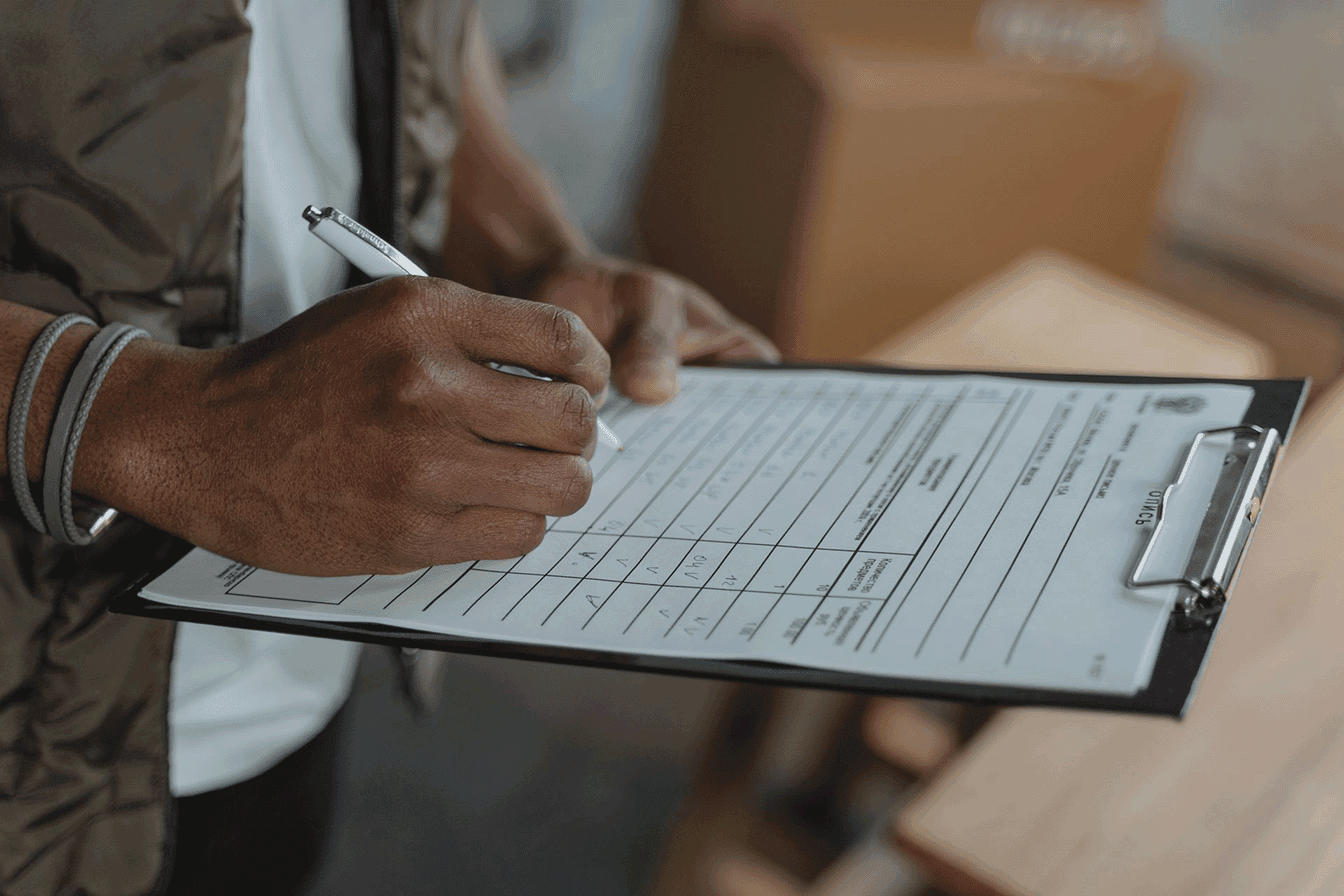 Person filling out a permit application on a clipboard