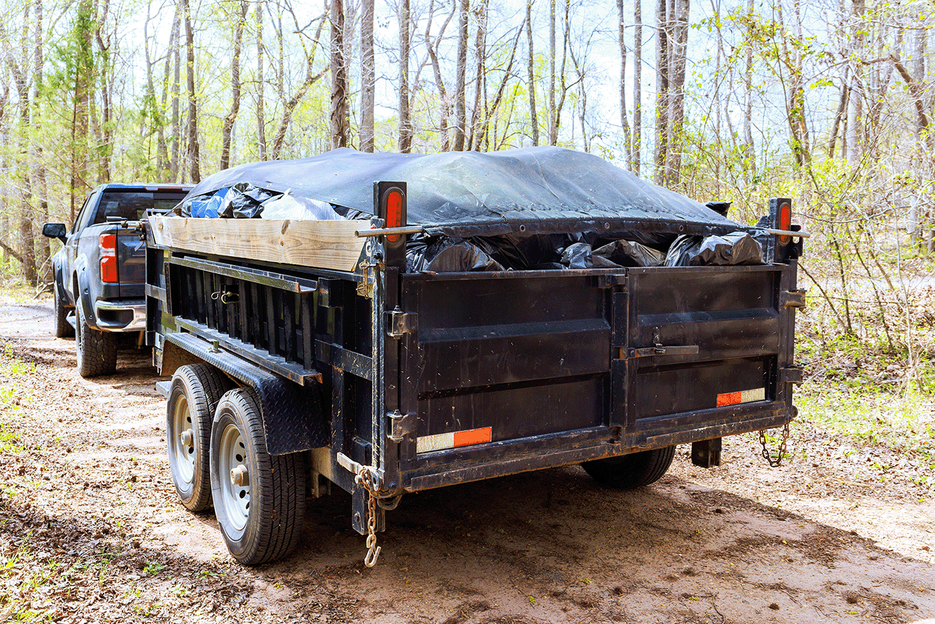 Loaded dump trailer hitched to a pickup truck on a dirt road